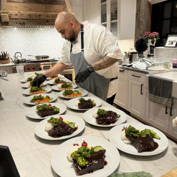 Chef plating multiple dishes in a kitchen.