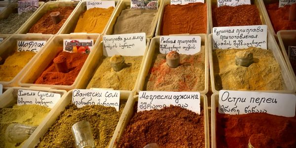 Various labeled spices in containers at a market.