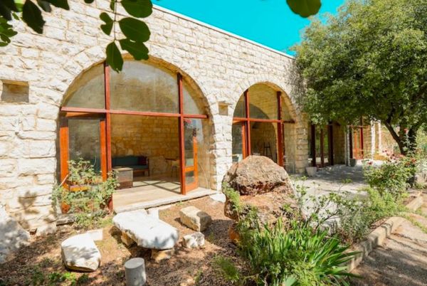 Stone house exterior with arches and garden.