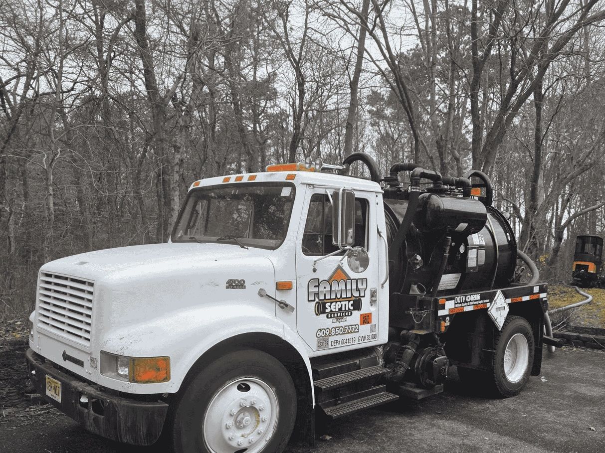 White septic service truck parked on a forest road.