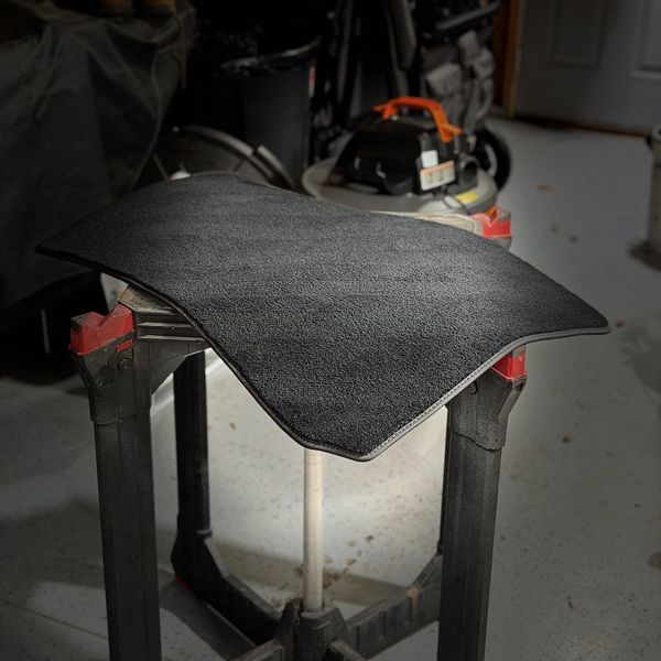 Black carpet mat on a stand in a garage.