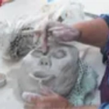 hands sculpting a clay face