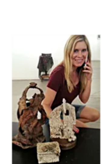 A young blonde woman posing next to Kathie's sculptures