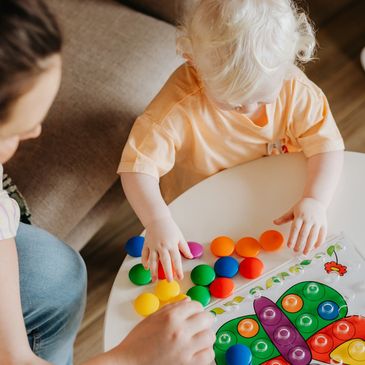 Toddler participating in early intervention ABA therapy activity with caregiver support
