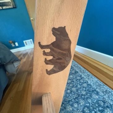 Bear silhouette carved on wooden furniture leg.