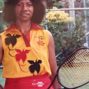 Woman in a colorful squash team outfit holding a racket.