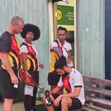 Four people in sports attire with squash equipment near a Samoa Commercial Bank sign.
