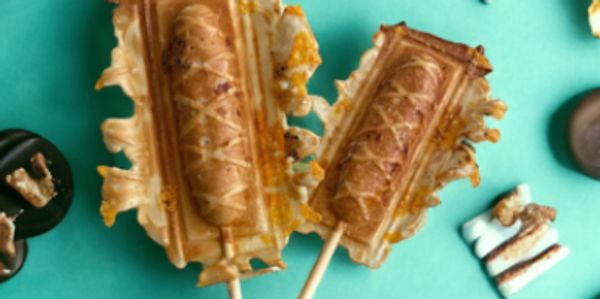 Two Bacon & Cheddar crepes on a stick on a teal background.