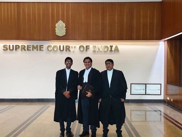 Three lawyers standing inside the Supreme Court of India.