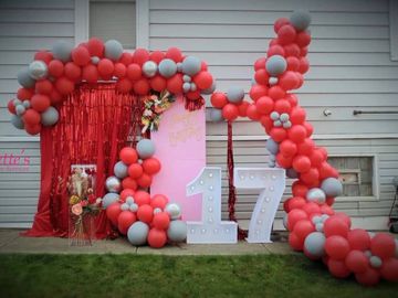 Bohemian dessert table set up with balloons and marquee number and backdrop with wall and curtains.