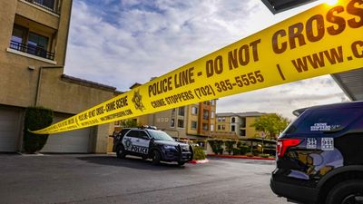Police cars behind yellow crime scene tape in a residential area.