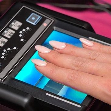 Manicured hand resting on a illuminated live scan fingerprint device