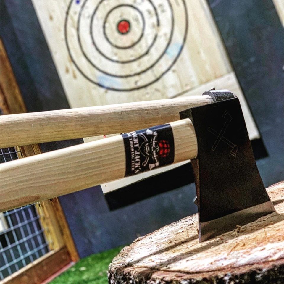 Two axes resting on a wooden chopping block with a target in the background.