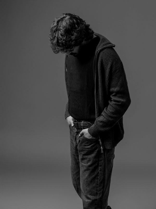 Man with curly hair looking down.