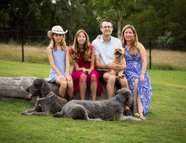 Austin family portrait with two daughters and three dogs in a grassy park.