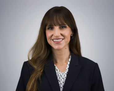Austin professional headshot of woman in navy blazer with natural smile on studio gray backdrop