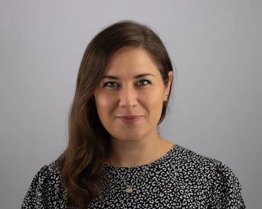 Professional headshot of Austin woman with long brown hair on neutral studio background
