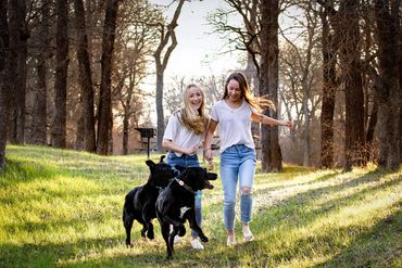 Austin senior portrait of two friends walking their dogs during an outdoor photo session in a park.