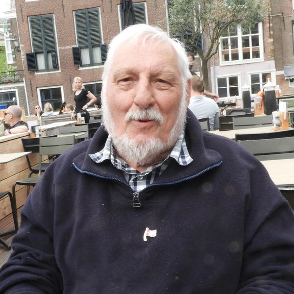 Elderly man sitting outdoors at a cafe, enjoying the day.
