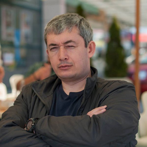 Man with gray hair and a serious expression wearing a black jacket.