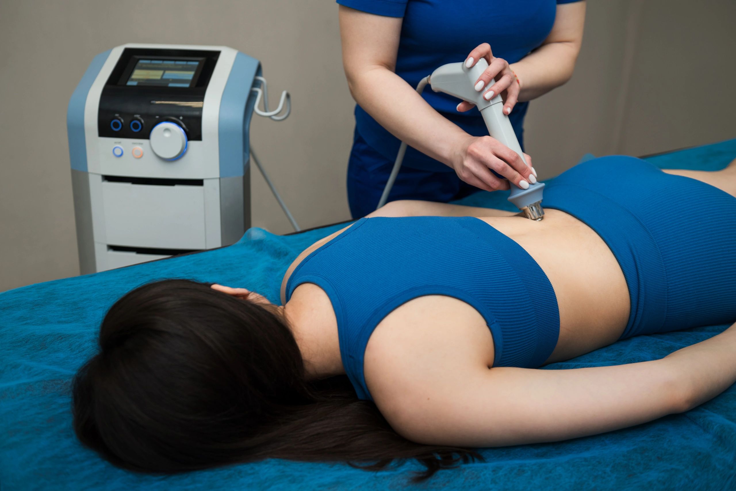 A healthcare professional uses a modern device on a patient's abdomen during a treatment