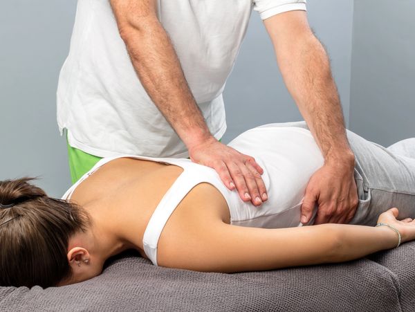Chiropractor adjusting patient's lower back during treatment.