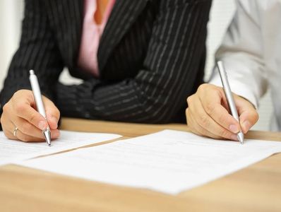 Two people signing a mediated settlement.