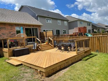Spacious wooden backyard deck with outdoor furniture under a sunny sky.