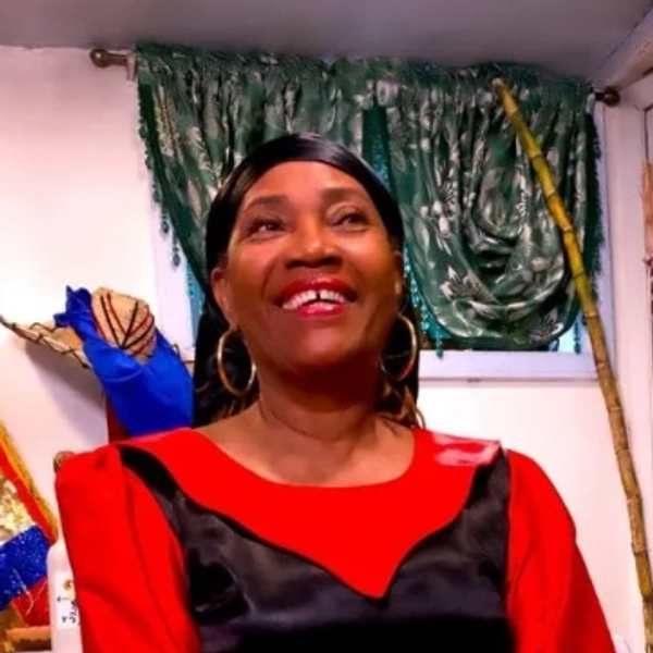 Smiling woman wearing a red and black outfit with gold hoop earrings.