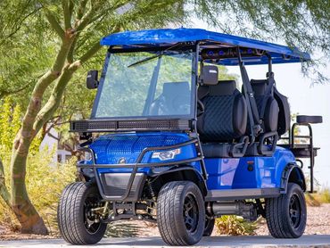 Blue golf cart parked on a sunny path with trees in the background.