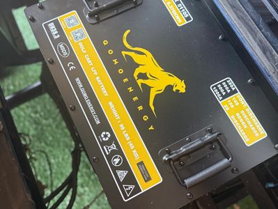 Close-up of a black battery box with yellow branding and safety labels.