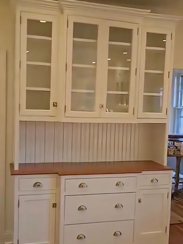 White wooden kitchen cabinet with glass doors and brown countertop.