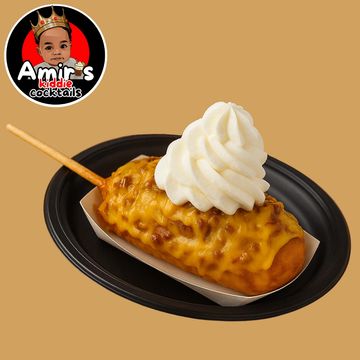A cheesy corndog topped with a swirl of whipped cream on a black plate.