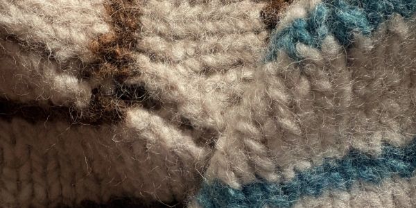 Close-up of knitted fabric with beige, blue, and brown yarn.