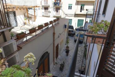A narrow courtyard with potted plants and parked cars in a residential area.
