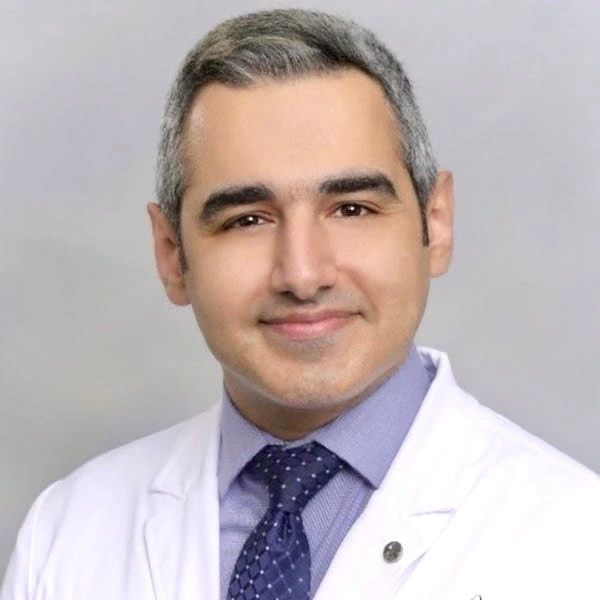 Portrait of a smiling man in white medical coat and tie.