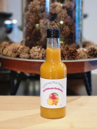 Bottle of Ladybug Hot Sauce Caribbean Sunburn on wooden table.