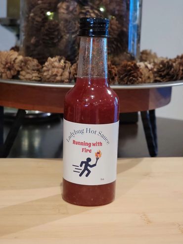 Bottle of Ladybug Hot Sauce labeled 'Running with Fire'.