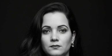 Black and white portrait of a woman with a serious expression against a dark background.