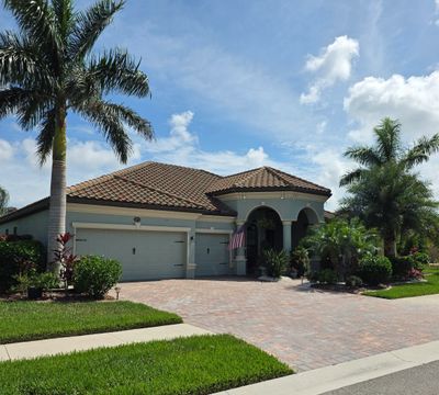 Single-story house with a tiled roof and palm trees under a blue sky.