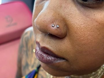 Close-up of a nose piercing with two studs.