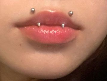 Close-up of lips with vampire-style lip and Monroe piercings.