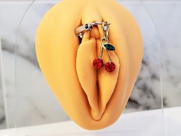 A cherry-themed piercing jewelry on a silicone model.