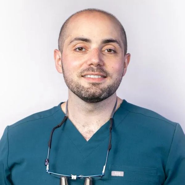 Portrait of a smiling male healthcare professional in teal scrubs.