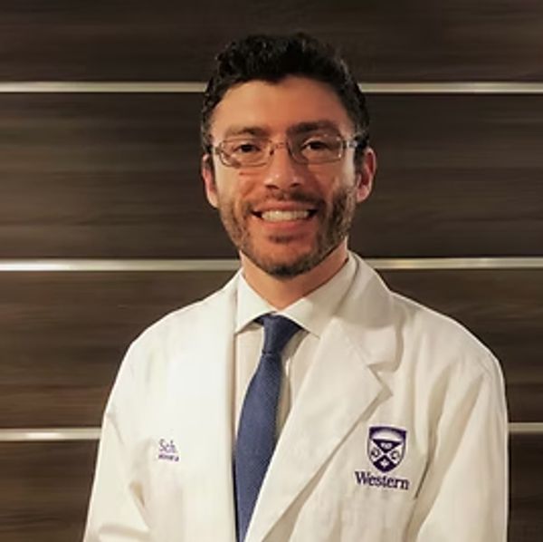 Smiling man in white medical coat and glasses.