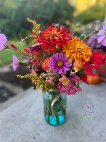 A vibrant bouquet of colorful flowers in a blue glass jar.