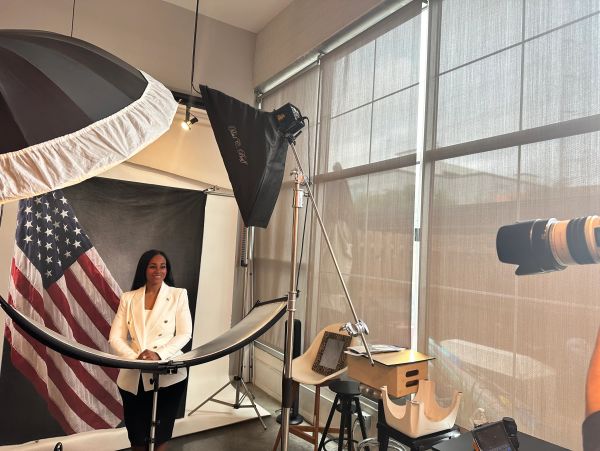 Woman posing for a photo shoot with an American flag backdrop.