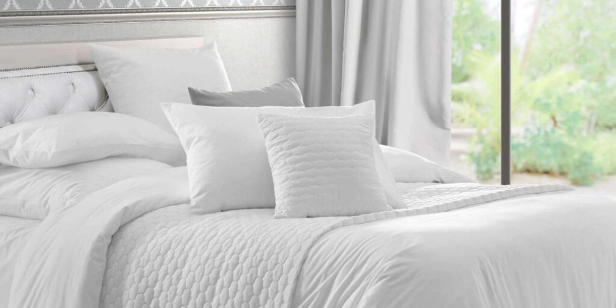 Luxurious white bedding with multiple pillows arranged on a cozy bed.