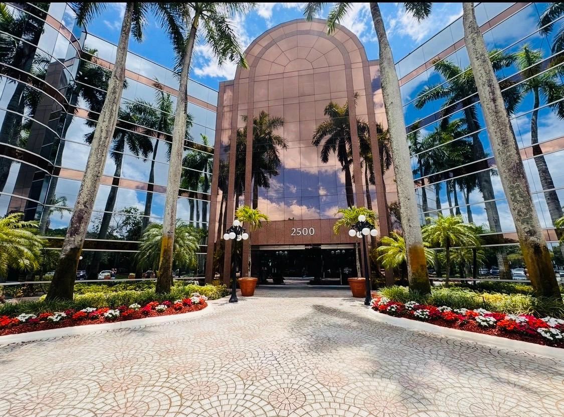 Modern office building with reflective glass and lush landscaping.