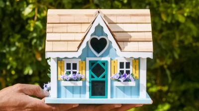 A small, decorative blue and white birdhouse with a heart-shaped cutout.